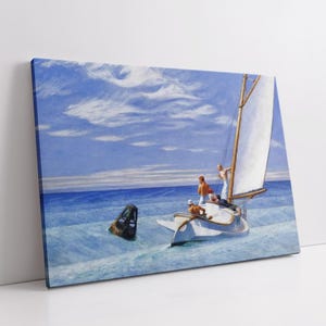 Op de afbeelding: Canvas print van een zeilboot op de oceaan onder een blauwe lucht met witte wolken. De boot heeft een wit zeil en verschillende mensen aan boord. Een zwarte boei drijft in het water bij de boot. Het kunstwerk wordt op een witte muur getoond.