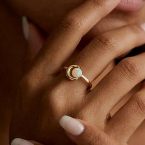 May include: A white ceramic mug with a black handle and the text "But First, Coffee" in a black, bold font. The mug is on a white surface. The mug is likely for hot beverages.