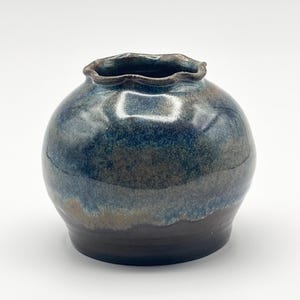 May include: A small, round ceramic vase with a scalloped rim. The vase is glazed in shades of blue, brown, and green.