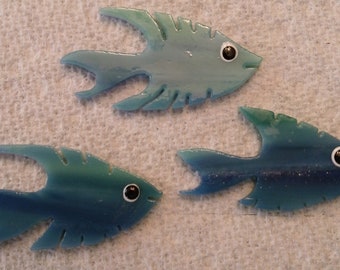 May include: Three blue glass fish with black eyes. The fish are different sizes and shapes. They are all made of glass and have a textured surface.