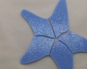 May include: A light blue, sparkly, ceramic starfish mosaic tile. The tile is made of several pieces of ceramic that have been joined together to form the shape of a starfish.