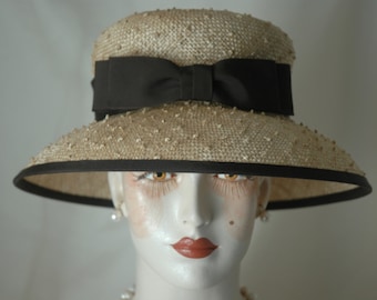 Puede incluir: Un sombrero de paja de ala ancha con una cinta de grosgrain negra y un lazo. El sombrero tiene una superficie texturizada y está ribeteado con una banda negra.