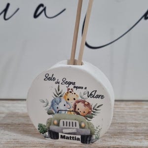 Può includere: Diffusore in ceramica bianca con un design di animali safari, tra cui un elefante, una giraffa e un leone in una jeep verde. È visibile anche il testo "Solo chi sogna impara a volare" e il nome "Mattia".