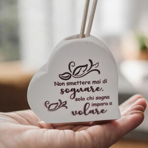 Può includere: Vaso bianco a forma di cuore in ceramica con una citazione in italiano che recita "Non smettere mai di sognare. Solo chi sogna impara a volare."