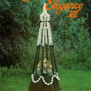May include: A hanging macrame plant holder featuring white and dark brown twisted cord sections, black beads, and a dark brown base with a white scalloped trim. The text Macrame Elegance VII and La Couronne is printed on the image.
