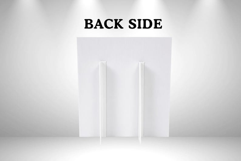 以下が含まれることがあります： 上部に黒い大文字でBACK SIDEと書かれた白い長方形のディスプレイボード。ボードの背面には2つの垂直な白い段ボール製のイーゼルスタンドが取り付けられており、直立した状態で安定感を保つ構造になっています。