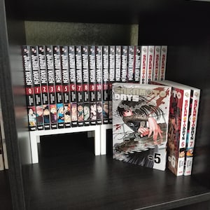 May include: A collection of manga books including Jujutsu Kaisen volumes 0 through 11 arranged in a row, alongside Sakamoto Days volumes 5, 6, and 7. The books feature black and white spines with red accents and illustrated covers with character art.