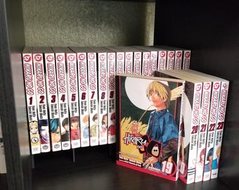 May include: A collection of Hikaru no Go manga volumes arranged on a shelf. The series includes volumes 1 through 9, 19, and 20 through 23. Volume 19 is displayed facing forward, featuring an illustration of a character with blonde hair and a blue shirt.