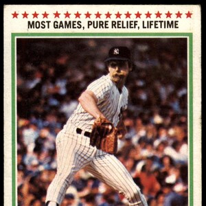 May include: Baseball card featuring Sparky Lyle in a New York Yankees uniform. The card has a white border with text at the top reading "MOST GAMES, PURE RELIEF, LIFETIME." The bottom of the card reads "'77 RECORD BREAKER" and "SPARKY LYLE."