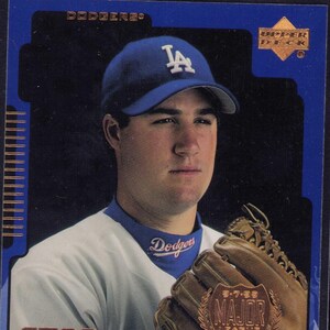 Puede incluir: Tarjeta de béisbol con Eric Gagne de los Dodgers de Los Ángeles. Lleva gorra y uniforme azul de los Dodgers. La tarjeta incluye el texto "Star Rookie" y "Major League Debut". El logo de Upper Deck es visible.