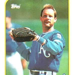 Könnte beinhalten: Eine Vintage-Baseballkarte von Topps mit George Brett von den Kansas City Royals. Die Karte zeigt Brett in einem blauen Trikot mit dem Royals-Logo, der einen Baseballhandschuh hält. Die Karte hat einen gelben Rand und das Topps-Logo.