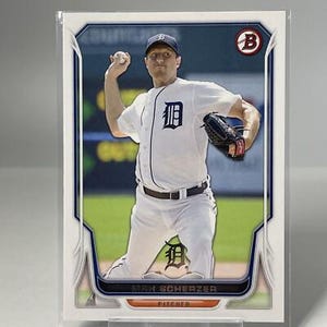 May include: Baseball card featuring Max Scherzer of the Detroit Tigers in a pitching pose. He wears a white uniform with the team logo and a navy blue cap. The card has a blue and white border with the Bowman logo.