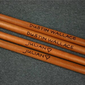 May include: Four wooden dowels with names engraved on them. The names are Dustin Wallace, Dustin Wallace, Julian, and Julian with a heart symbol.