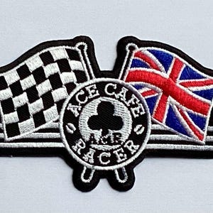 May include: Embroidered patch featuring a checkered racing flag and a Union Jack flag. The patch includes the text "ACE CAFE RACER" in a circular design, with a black and white color scheme and wing accents.
