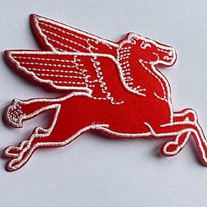 Puede incluir: Un parche bordado rojo que representa un caballo alado, o Pegaso, en una pose de carrera. El parche tiene un contorno blanco y costuras detalladas en las alas y el cuerpo, creando un efecto texturizado. Adecuado para ropa o accesorios.