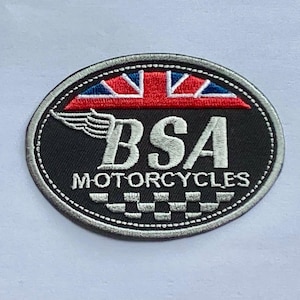 Puede incluir: Parche ovalado negro con el texto "BSA MOTORCYCLES" en blanco. La parte superior del parche presenta un diseño rojo, blanco y azul. Un gráfico de ala blanca está en el lado izquierdo del texto. El parche tiene un borde cosido blanco.