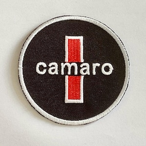 May include: Round black patch with the word "camaro" in white, centered over a red vertical rectangle. The patch has a white stitched border.