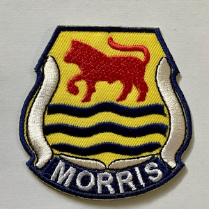 May include: Embroidered patch with a yellow background, featuring a red bull above blue wavy lines. The patch has a white border with blue trim and the name "MORRIS" in white letters.