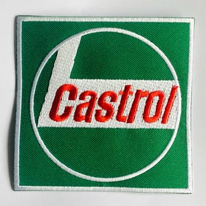 May include: Embroidered patch featuring the Castrol logo. The patch has a green background with a white border. The logo includes a white 'L' shape within a white circle, and the word 'Castrol' in red.