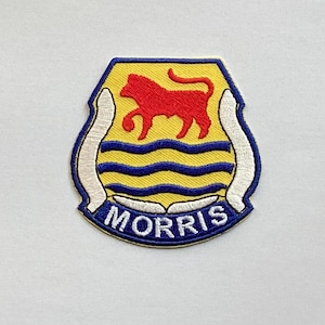 May include: Embroidered patch with a yellow background and a red bull emblem. The patch features blue wavy lines and the name "MORRIS" in white lettering on a blue border. The patch is approximately 3 inches wide and 3 inches tall.