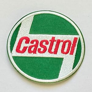 May include: Embroidered patch featuring the Castrol logo. The patch is circular, with a green background and a white border. The word "Castrol" is in red, with white accents. The design is a classic automotive emblem.