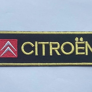 May include: Black rectangular patch with the Citroën logo embroidered in gold. The logo features two white chevrons inside a red square. The word "CITROËN" is embroidered in gold.