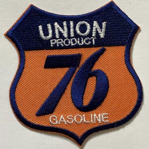 May include: Embroidered patch in a shield shape, featuring the text "UNION PRODUCT" above the number "76" and the word "GASOLINE". The patch has a blue border and accents, with an orange background.