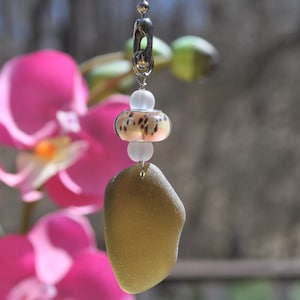 May include: A green sea glass charm with a silver clasp and white and brown glass beads.