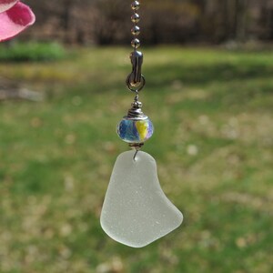 May include: A white sea glass fan pull with a colorful glass bead and a silver chain.