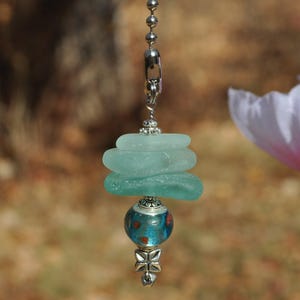 May include: A light blue glass fan pull with a silver chain and a blue and red glass bead.
