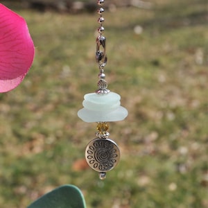 May include: A silver ceiling fan pull chain with a stack of three light blue sea glass pieces and a silver charm with a swirl design.