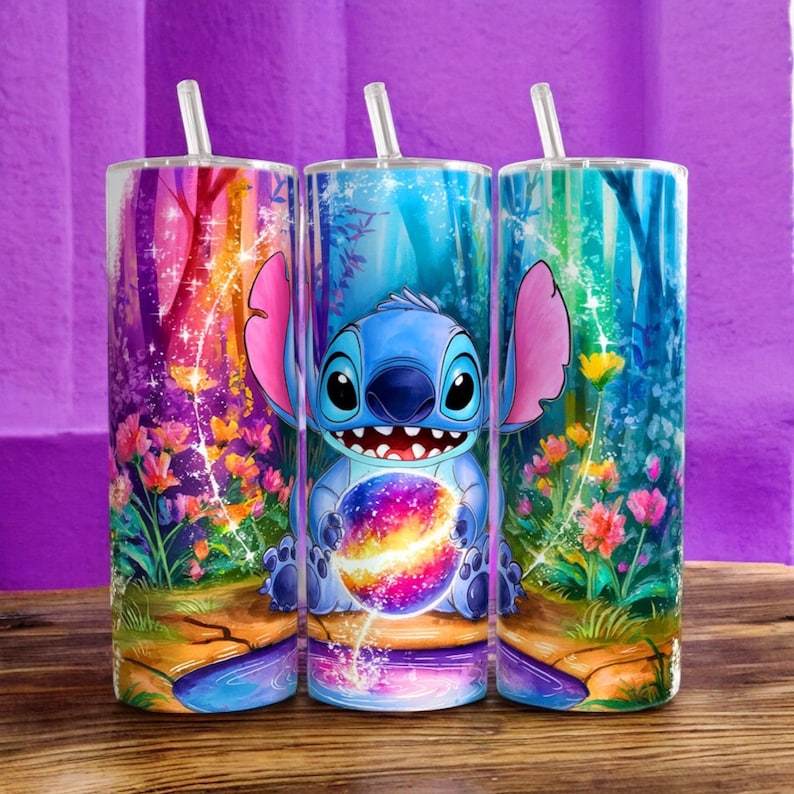 Puede incluir: Tres vasos de acero inoxidable con pajitas, con un dise&ntilde;o de bosque colorido y un personaje de dibujos animados sosteniendo una galaxia. El personaje tiene piel azul, orejas grandes y una amplia sonrisa. El fondo incluye flores y &aacute;rboles.