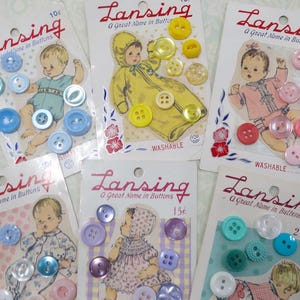 May include: Six vintage Lansing button cards featuring illustrations of infants in various outfits. Each card displays a collection of small, round, multi-colored plastic buttons in shades of blue, yellow, pink, purple, and teal, with prices marked.