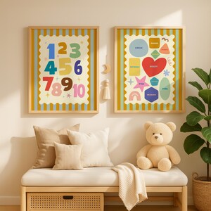 May include: Two framed educational prints with a light yellow border. One features numbers 1-10 in various colors, and the other displays shapes with their names. A beige teddy bear sits on a bench below.