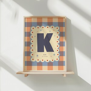 Puede incluir: Impresi&oacute;n art&iacute;stica enmarcada con una gran letra 'K' azul marino sobre un fondo crema, bordeada por un borde festoneado. El fondo tiene un patr&oacute;n de cuadros en naranja, azul y crema. La impresi&oacute;n incluye el nombre 'KAI' y la fecha '07.14.2024'.