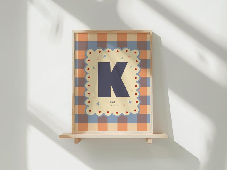 Puede incluir: Impresi&oacute;n art&iacute;stica enmarcada con una gran letra 'K' azul marino sobre un fondo crema, bordeada por un borde festoneado. El fondo tiene un patr&oacute;n de cuadros en naranja, azul y crema. La impresi&oacute;n incluye el nombre 'KAI' y la fecha '07.14.2024'.