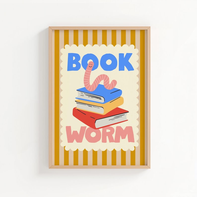 May include: A framed print featuring a stack of books with a cartoon worm on top. The word "BOOK" is in blue, and "WORM" is in pink. The background is a cream color with a yellow and white striped border.