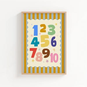May include: A framed print featuring colorful numbers 1 through 10. The numbers are in various colors, including blue, yellow, green, and pink, set against a cream-colored background with a scalloped edge. The frame has a striped pattern.