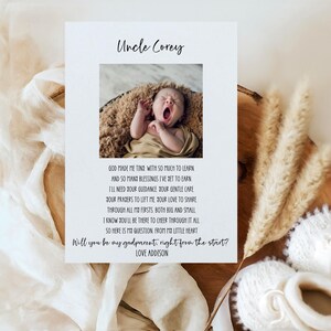 Puede incluir: Una tarjeta blanca con una foto de un bebé bostezando, el texto "Uncle Corey" y un poema. La tarjeta está rodeada de elementos decorativos, incluyendo plantas secas y patucos de bebé.