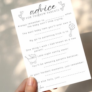 May include: A white card with the text "advice FOR THE NEW PARENTS" and fill-in-the-blank prompts. The card includes illustrations of hearts, a baby rattle, and a baby carriage. The card is held by a hand.
