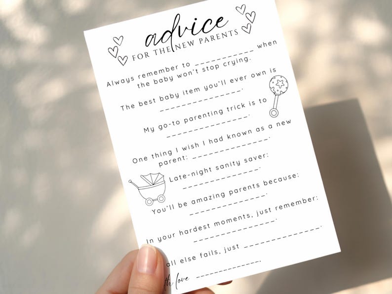May include: A white card with the text "advice FOR THE NEW PARENTS" and fill-in-the-blank prompts. The card includes illustrations of hearts, a baby rattle, and a baby carriage. The card is held by a hand.