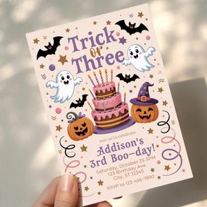 May include: A Halloween-themed invitation with the text "Trick or Three" and "Addison's 3rd Boo-day!". The design includes cartoon ghosts, bats, pumpkins, a cake, and stars. The invitation is held by a hand.