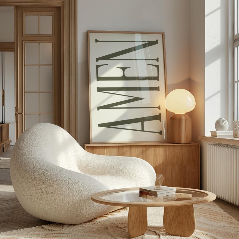 K&ouml;nnte beinhalten: Ein wei&szlig;er, flauschiger, runder Sessel mit einem Holz-Couchtisch davor. Ein gerahmtes Poster mit dem Wort "AMEN" in dunkelgr&uuml;nen Buchstaben h&auml;ngt an der Wand. Eine wei&szlig;e Lampe mit einem Holzsockel steht auf einem Holzregal.