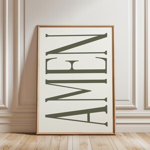 K&ouml;nnte beinhalten: Ein gerahmter Druck mit dem Wort "AMEN" in gro&szlig;en, stilisierten, dunkelgr&uuml;nen Buchstaben auf wei&szlig;em Hintergrund.