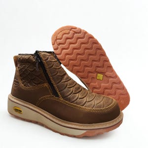 May include: A brown leather ankle boot featuring a textured scale pattern on the upper, a side zipper closure, and a thick beige midsole. The outsole is a light brown rubber with a wavy tread pattern and a small yellow logo badge on the heel.