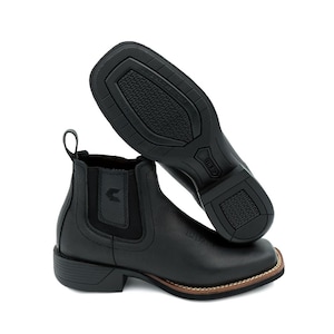 May include: Black leather ankle boots with a square toe and elastic side panels. The boots have a pull tab at the back and a brown stitched sole. The soles are black with a textured pattern. The boots are designed for comfort and style.