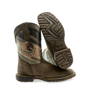 May include: A pair of brown leather western-style boots featuring a printed Mexican coat of arms on the shaft. The boots have a dark brown sole with a textured tread pattern, yellow stitching along the welt, and the brand name CEBU on the heel.