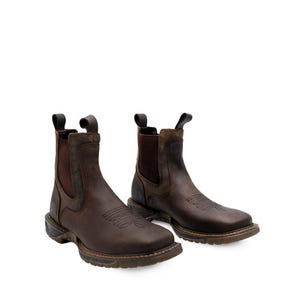 May include: A pair of brown leather Chelsea boots with square toes. The boots have elastic side panels and pull tabs. The soles are dark brown with a textured design. The boots are designed for work and outdoor activities.