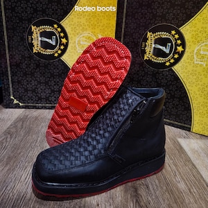 May include: Black leather rodeo boots with a woven design on the upper and a red sole. The boots have a side zipper and are displayed with the red sole facing up. The text "Rodeo boots" is visible.