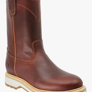 May include: Brown leather work boot with a white and tan sole. The boot has a pull-on design with a rounded toe and a mid-calf height. The stitching is visible in a contrasting color, and the boot has a sturdy, durable construction.